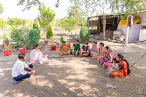 A diverse group gathered for a community meeting in rural Nagpur, India, discussing agriculture.